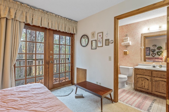 bedroom featuring access to outside, ensuite bath, light carpet, a textured ceiling, and sink