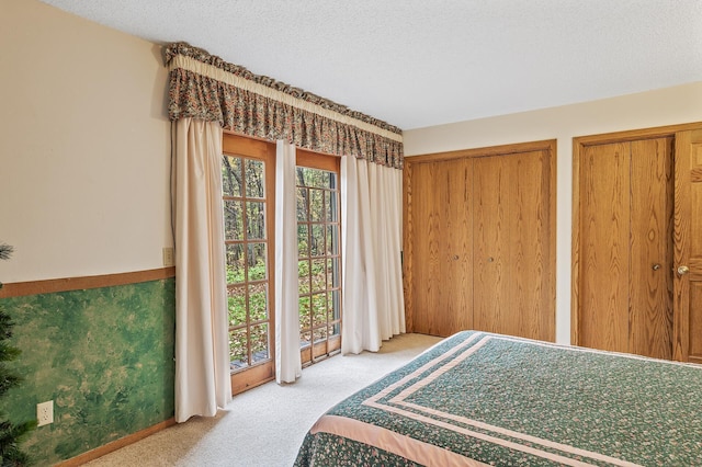 carpeted bedroom with a textured ceiling and two closets