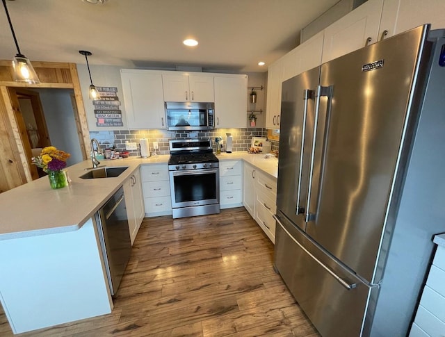 kitchen featuring appliances with stainless steel finishes, tasteful backsplash, hanging light fixtures, white cabinets, and sink