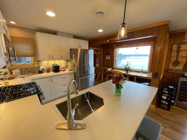 kitchen featuring pendant lighting, white cabinets, beverage cooler, sink, and stainless steel refrigerator