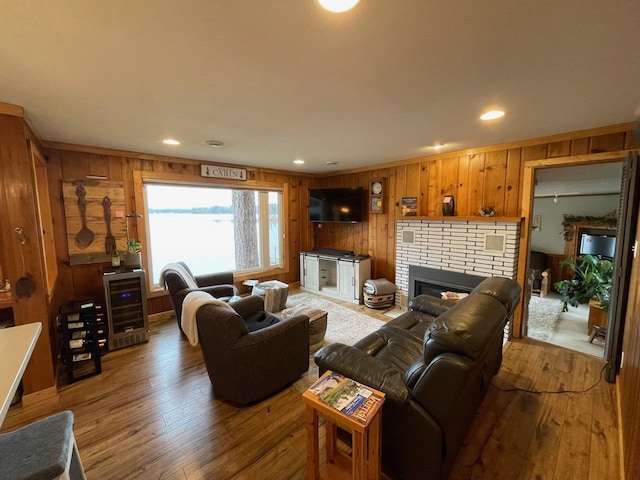 living room with a fireplace, hardwood / wood-style floors, ornamental molding, and wine cooler