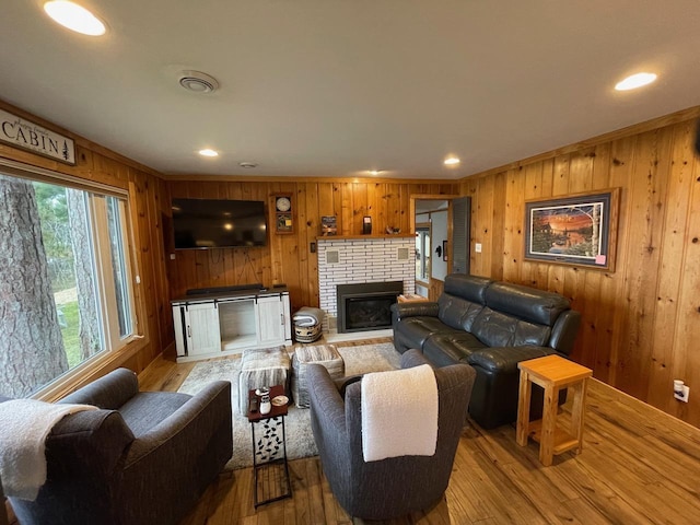 living room featuring crown molding, light hardwood / wood-style floors, a fireplace, and wood walls