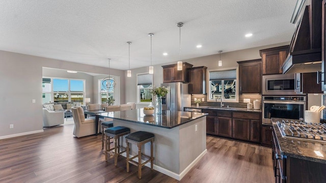 kitchen featuring a kitchen island, dark hardwood / wood-style flooring, stainless steel appliances, and hanging light fixtures