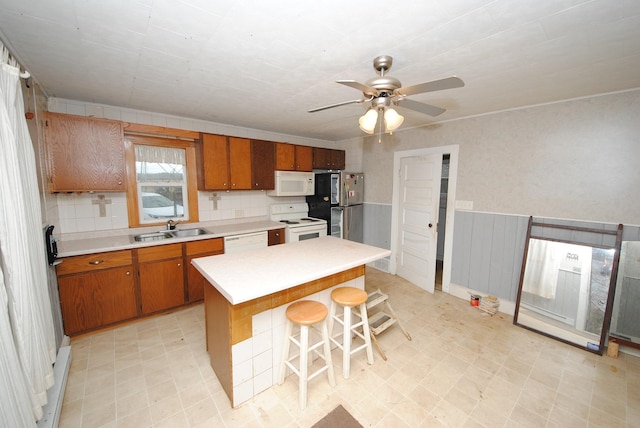 kitchen with a center island, a breakfast bar area, sink, ceiling fan, and white appliances