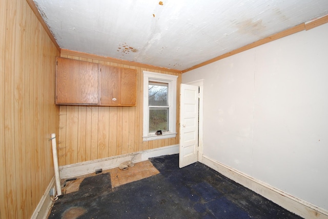 unfurnished room with wood walls and crown molding