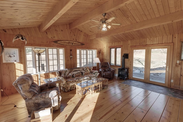 living room featuring wood ceiling, a wood stove, wood walls, and lofted ceiling with beams