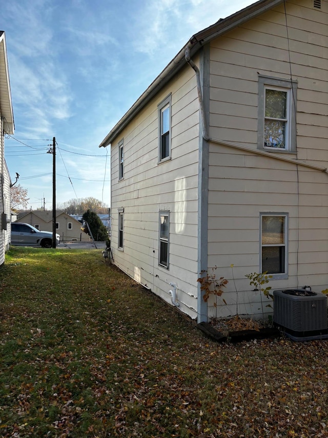 view of side of property featuring central AC unit and a yard