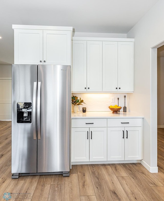 kitchen with white cabinetry, stainless steel fridge, light wood-type flooring, and decorative backsplash