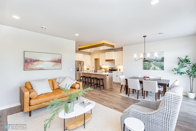 living room featuring sink, a notable chandelier, and light hardwood / wood-style floors