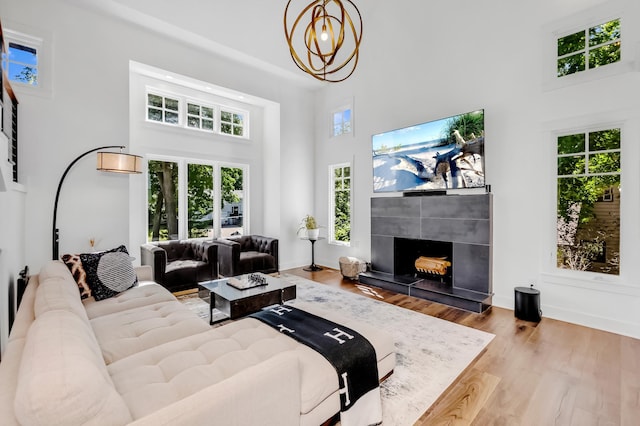 living room featuring a fireplace, a healthy amount of sunlight, a high ceiling, and light wood-type flooring