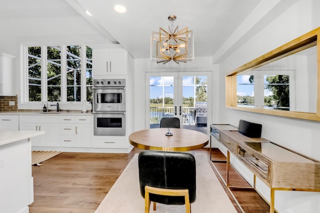 kitchen with french doors, double oven, pendant lighting, white cabinets, and light wood-type flooring