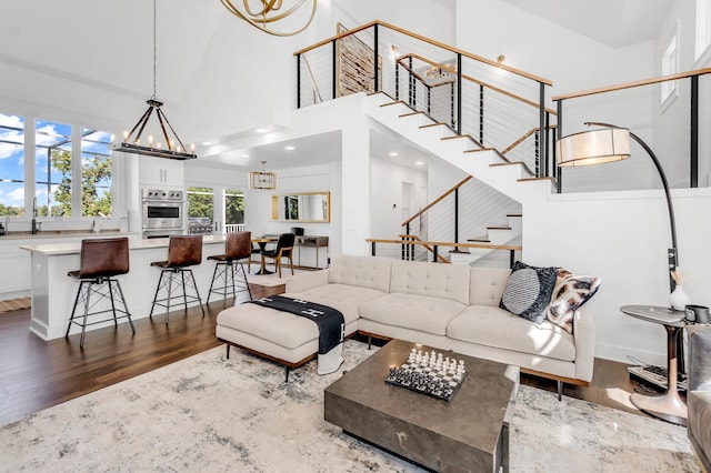 living room with a towering ceiling, a notable chandelier, and dark hardwood / wood-style flooring