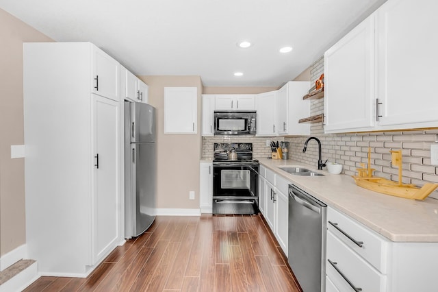 kitchen featuring sink, hardwood / wood-style flooring, white cabinetry, and black appliances