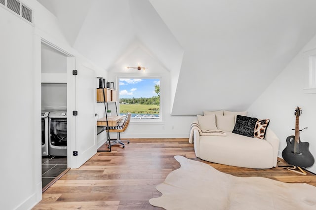 living area featuring washer and dryer, vaulted ceiling, and light hardwood / wood-style flooring