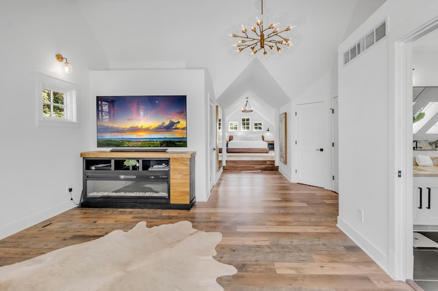 interior space featuring hardwood / wood-style flooring, an inviting chandelier, a wealth of natural light, and lofted ceiling