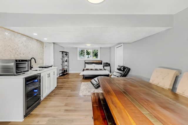 bedroom featuring light hardwood / wood-style floors, wine cooler, and indoor wet bar