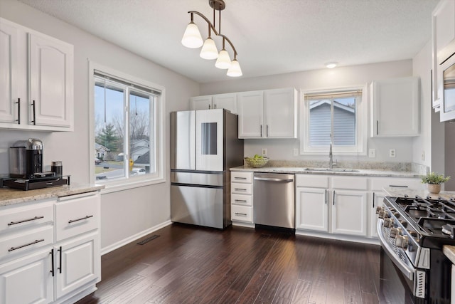 kitchen featuring pendant lighting, sink, dark hardwood / wood-style flooring, white cabinetry, and stainless steel appliances