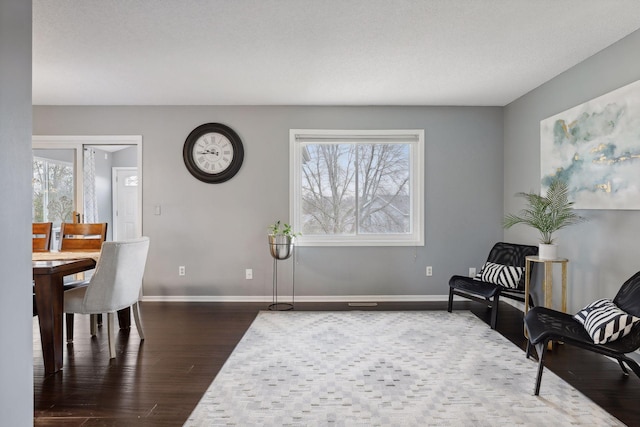 living area featuring a textured ceiling, a healthy amount of sunlight, and dark hardwood / wood-style floors