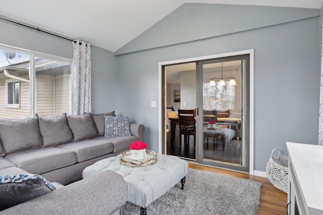 living room featuring hardwood / wood-style floors, lofted ceiling, and a notable chandelier