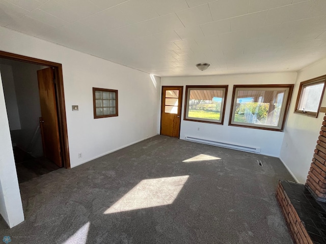 empty room with dark colored carpet, a baseboard radiator, and plenty of natural light