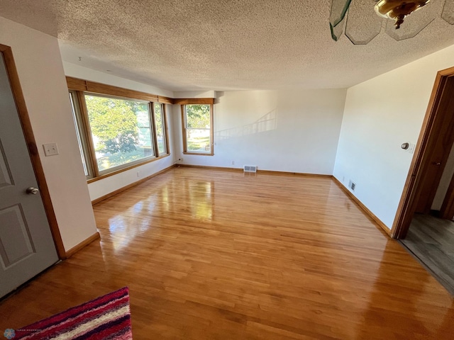 unfurnished room featuring light hardwood / wood-style floors and a textured ceiling