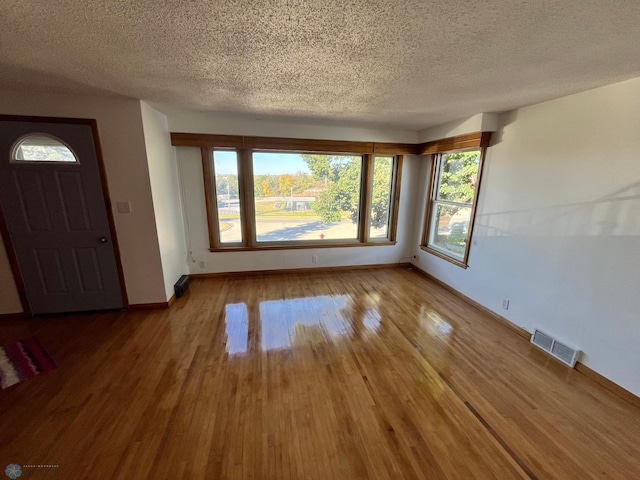 interior space with a textured ceiling and hardwood / wood-style flooring