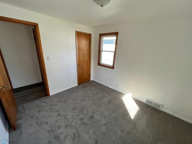 unfurnished bedroom with a closet and dark colored carpet