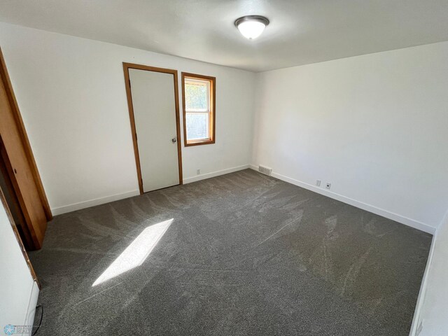 unfurnished room featuring dark carpet