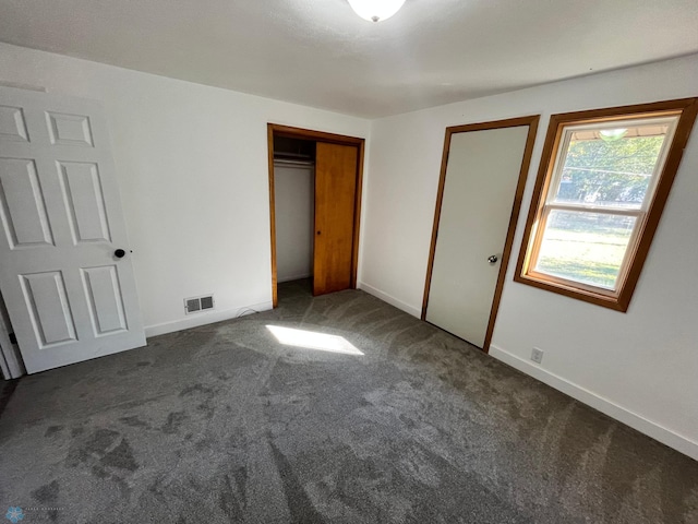 unfurnished bedroom featuring a closet and dark colored carpet