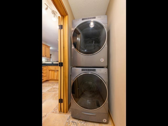 laundry room featuring a textured ceiling and stacked washer and dryer