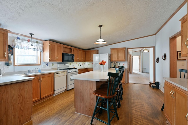 kitchen featuring a center island, hanging light fixtures, wood-type flooring, white appliances, and a breakfast bar area