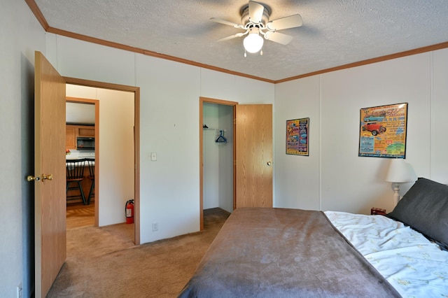 bedroom featuring ceiling fan, light colored carpet, a textured ceiling, and crown molding