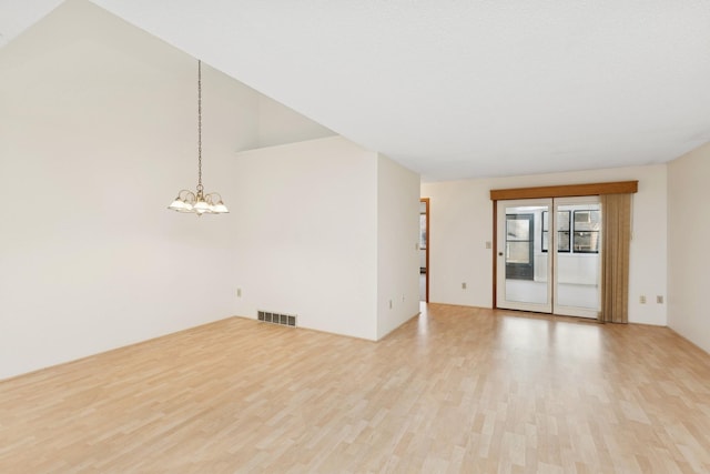 unfurnished room featuring light wood-type flooring and an inviting chandelier