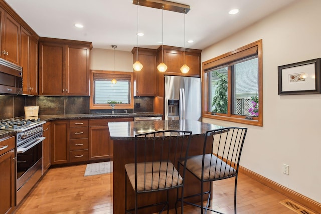 5006 Sheridan Ave S, Minneapolis, MN 55410 - kitchen with appliances with stainless steel finishes, light wood-style floors, a sink, tasteful backsplash, and a kitchen bar