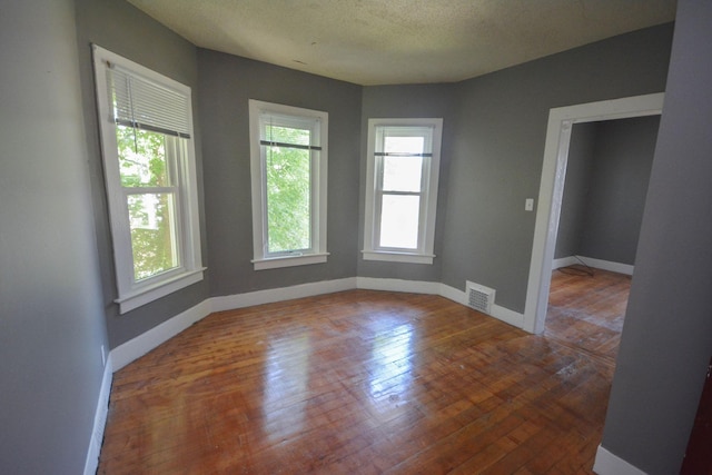 spare room featuring wood-type flooring and a textured ceiling