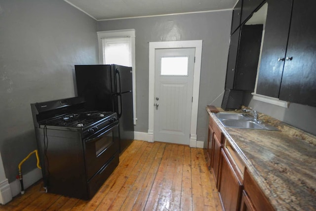 107 3rd Ave SW, Austin, MN 55912 - kitchen featuring dark stone countertops, sink, black appliances, and light wood-type flooring