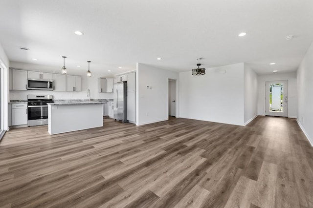 kitchen with hanging light fixtures, a kitchen island, stainless steel appliances, and wood-type flooring