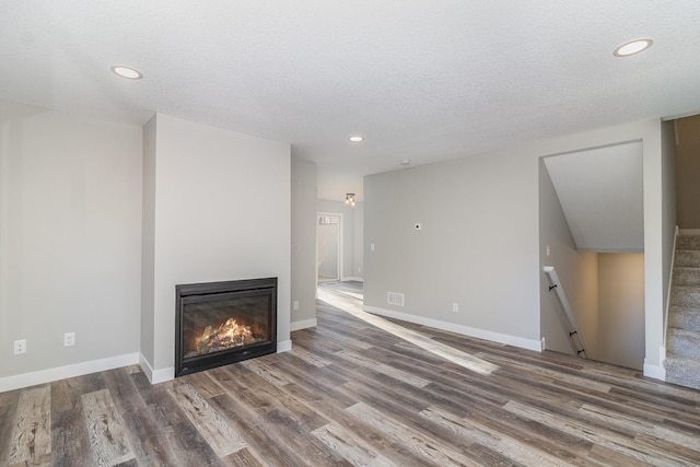 unfurnished living room featuring dark hardwood / wood-style flooring and a textured ceiling