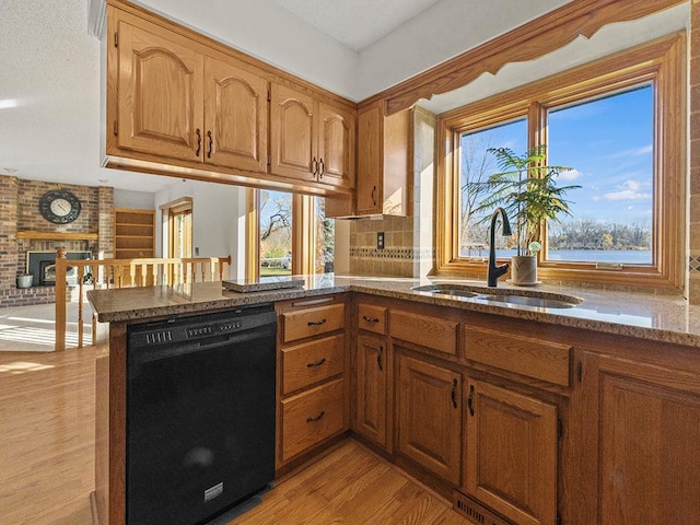 kitchen featuring dishwasher, sink, kitchen peninsula, light hardwood / wood-style floors, and a fireplace