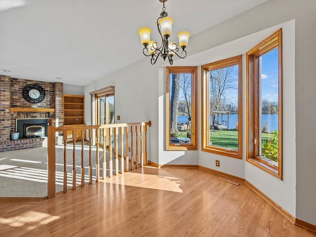 interior space featuring a chandelier, a water view, plenty of natural light, and light hardwood / wood-style floors