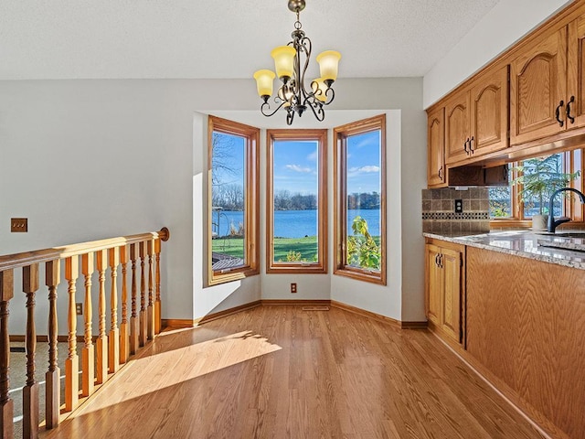 kitchen with a chandelier, pendant lighting, a water view, and a wealth of natural light