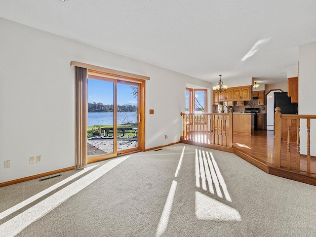 carpeted living room featuring a chandelier and a water view