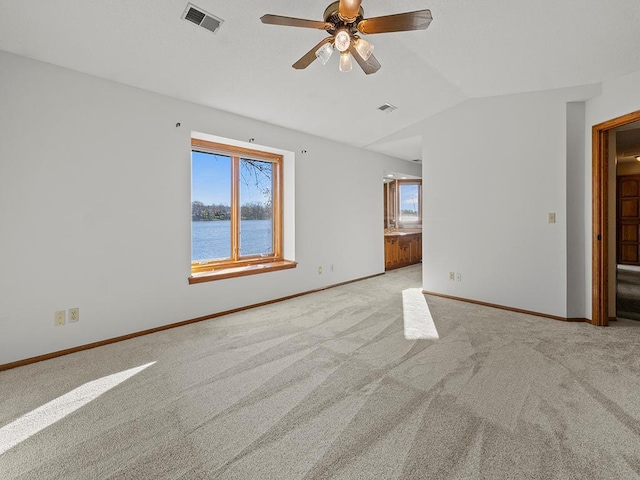 carpeted spare room featuring ceiling fan, a water view, and vaulted ceiling