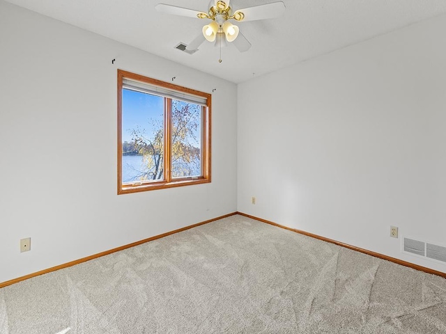 carpeted spare room featuring a water view and ceiling fan