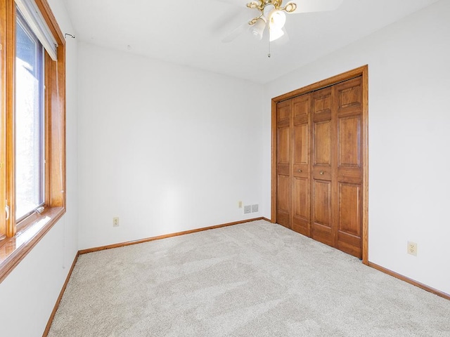 unfurnished bedroom with carpet floors, a closet, and ceiling fan