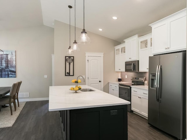 kitchen featuring appliances with stainless steel finishes, vaulted ceiling, a kitchen island with sink, and sink