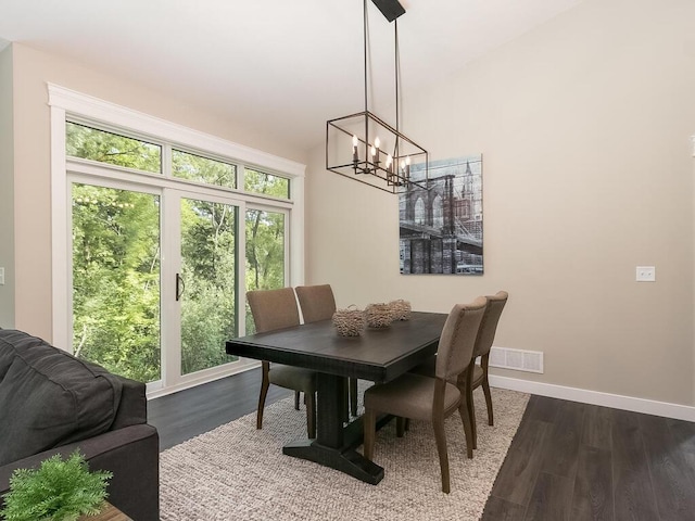 dining space featuring wood-type flooring and an inviting chandelier