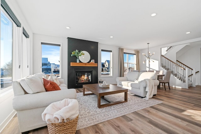 living room with a chandelier, light wood-type flooring, and a large fireplace