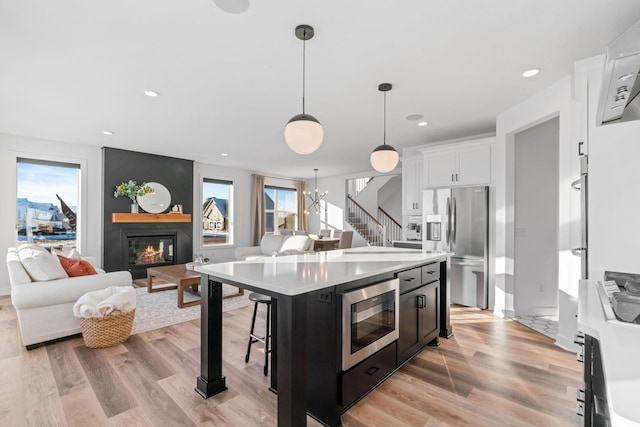 kitchen with pendant lighting, a center island, appliances with stainless steel finishes, a kitchen bar, and white cabinetry