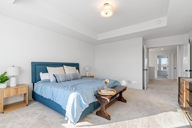 bedroom with a raised ceiling and light carpet